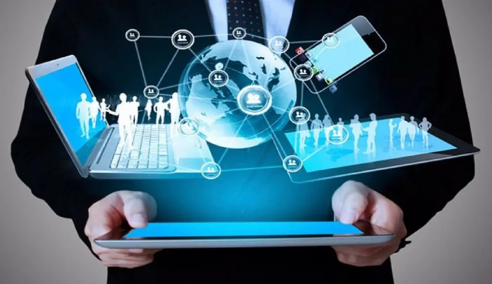 Un uomo d'affari tiene in mano un tablet da cui si proiettano immagini di Business Objects interconnessi, con icone rappresentanti persone, la comunicazione e la globalizzazione, simboleggiando l'innovazione e la gestione aziendale nel mondo digitale.
